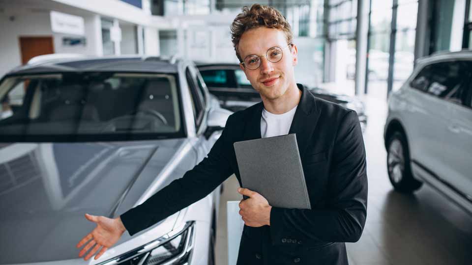 Ein Verkäufer zeigt auf ein Auto und erklärt dem Kunden die Konditionen beim Auto verkaufen Bamberg